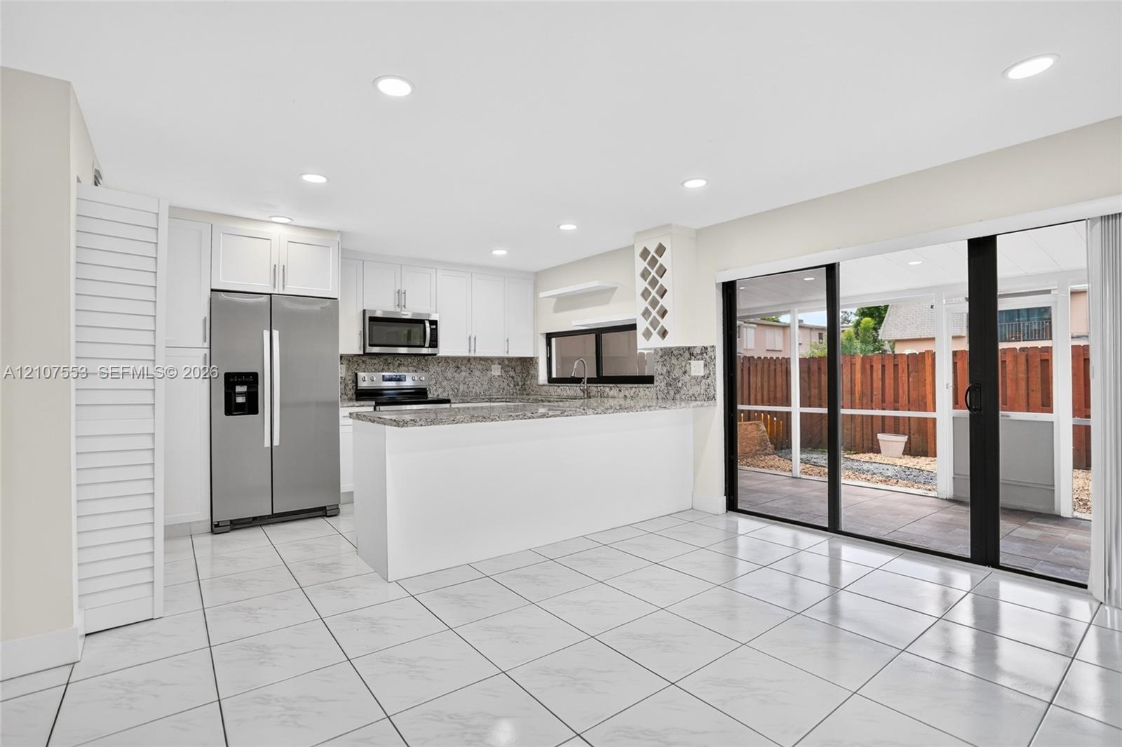 Kitchen featuring white cabinetry, stone-finish countertops, stainless steel appliances, built-in wine rack, and tile flooring throughout