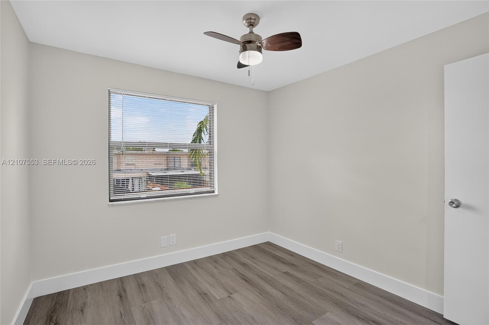 Neutral wall finishes, wood-finish flooring, and a ceiling fan with integrated lighting