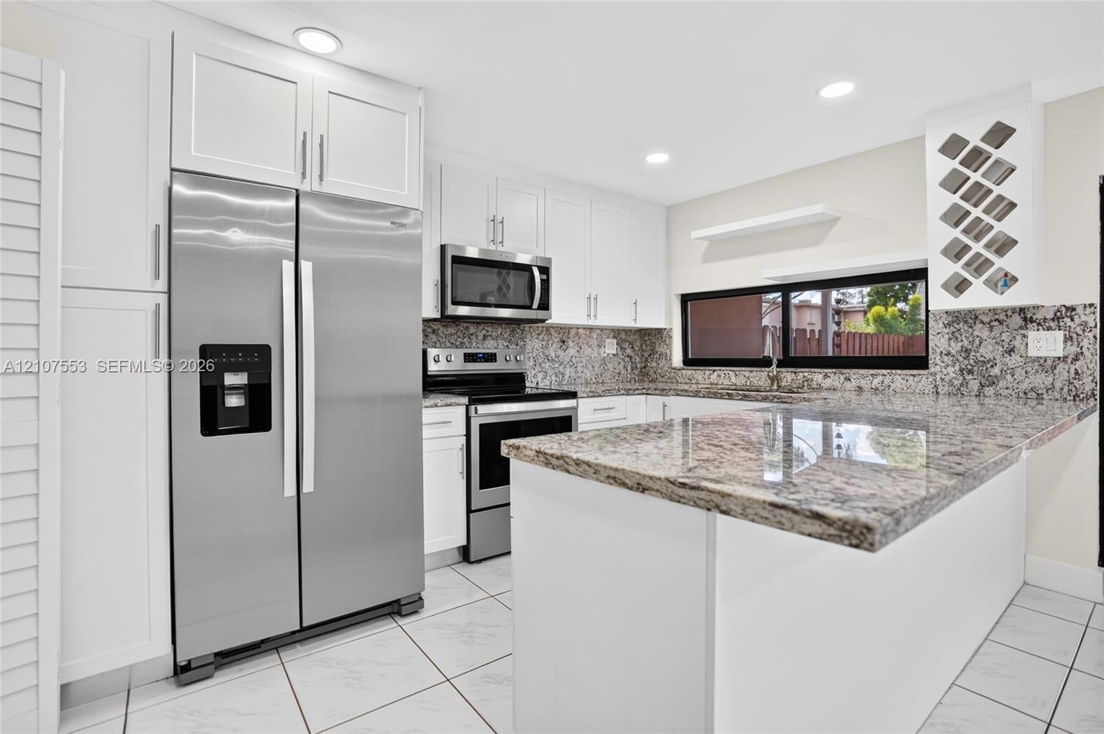 Kitchen featuring white cabinetry, stone-surface countertops, stainless steel appliances, a built-in wine rack, and tile flooring