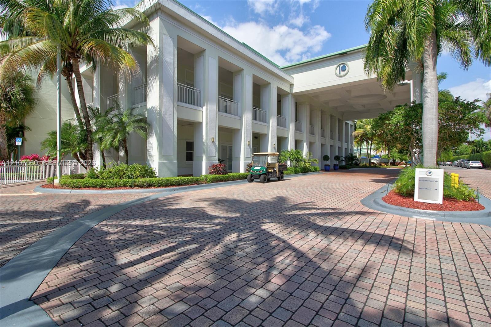 Multi-story exterior featuring a grand porte-cochre, prominent architectural columns, covered balconies, and a paver stone motor court