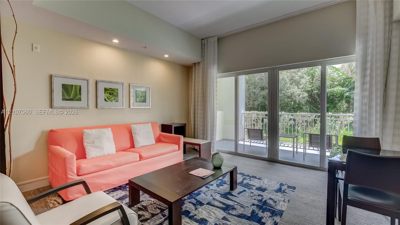Living area featuring high ceilings, recessed lighting, and expansive sliding glass doors providing access to a covered balcony with metal railing