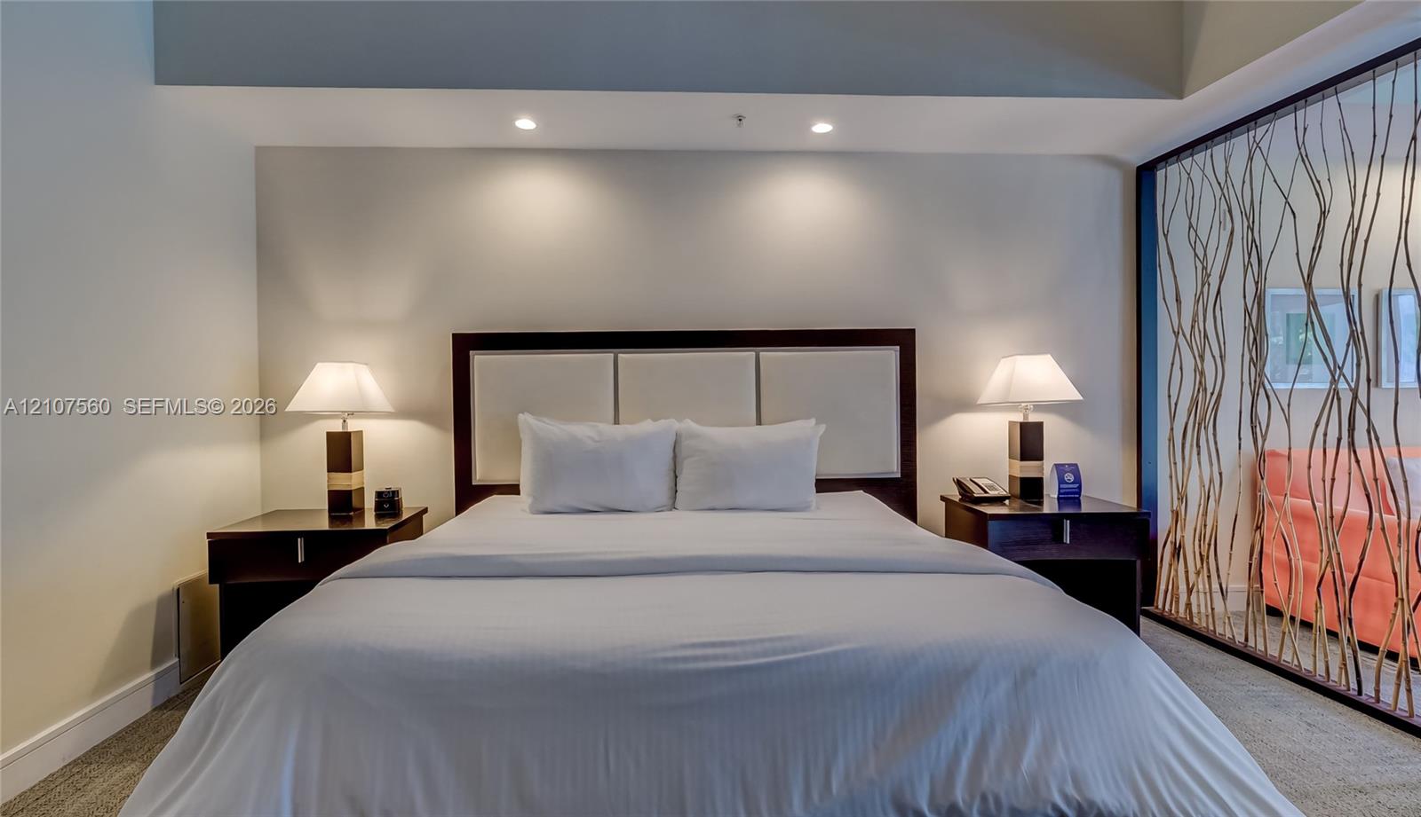 Built-in rectangular headboard with upholstered paneling and decorative room divider featuring an organic branch-inspired screen