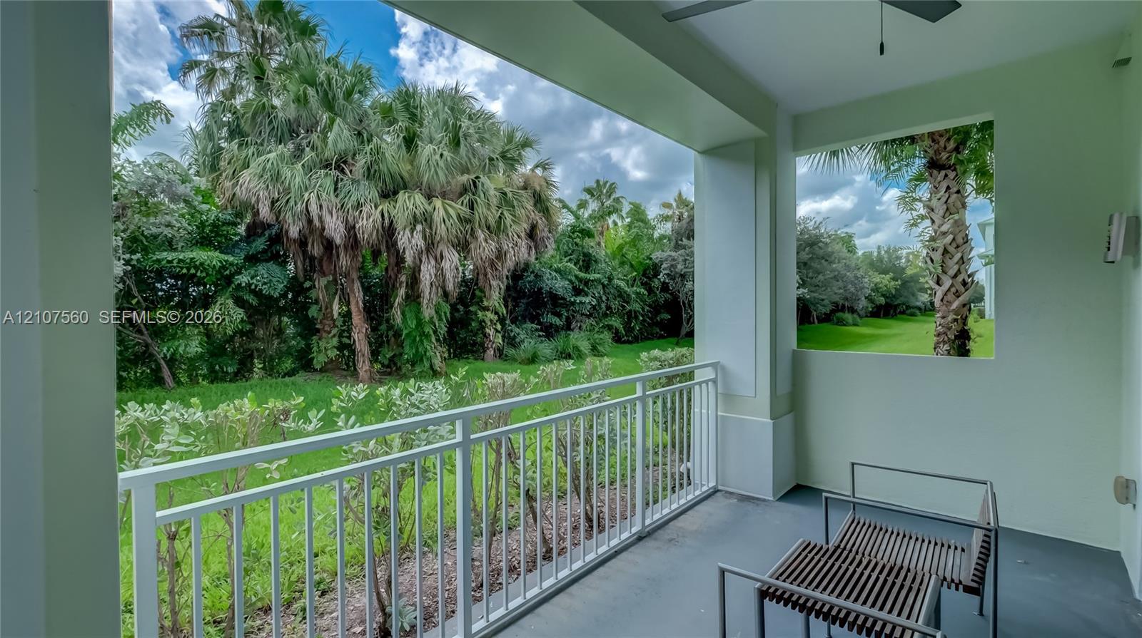 Covered balcony featuring white metal railings, concrete flooring, and an integrated ceiling fan