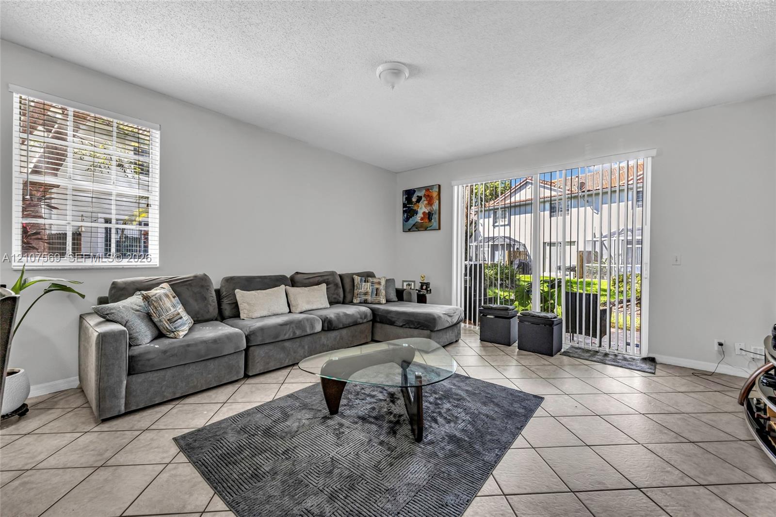 Living space featuring light-toned ceramic tile flooring, a multi-pane window, and a sliding glass door providing external access