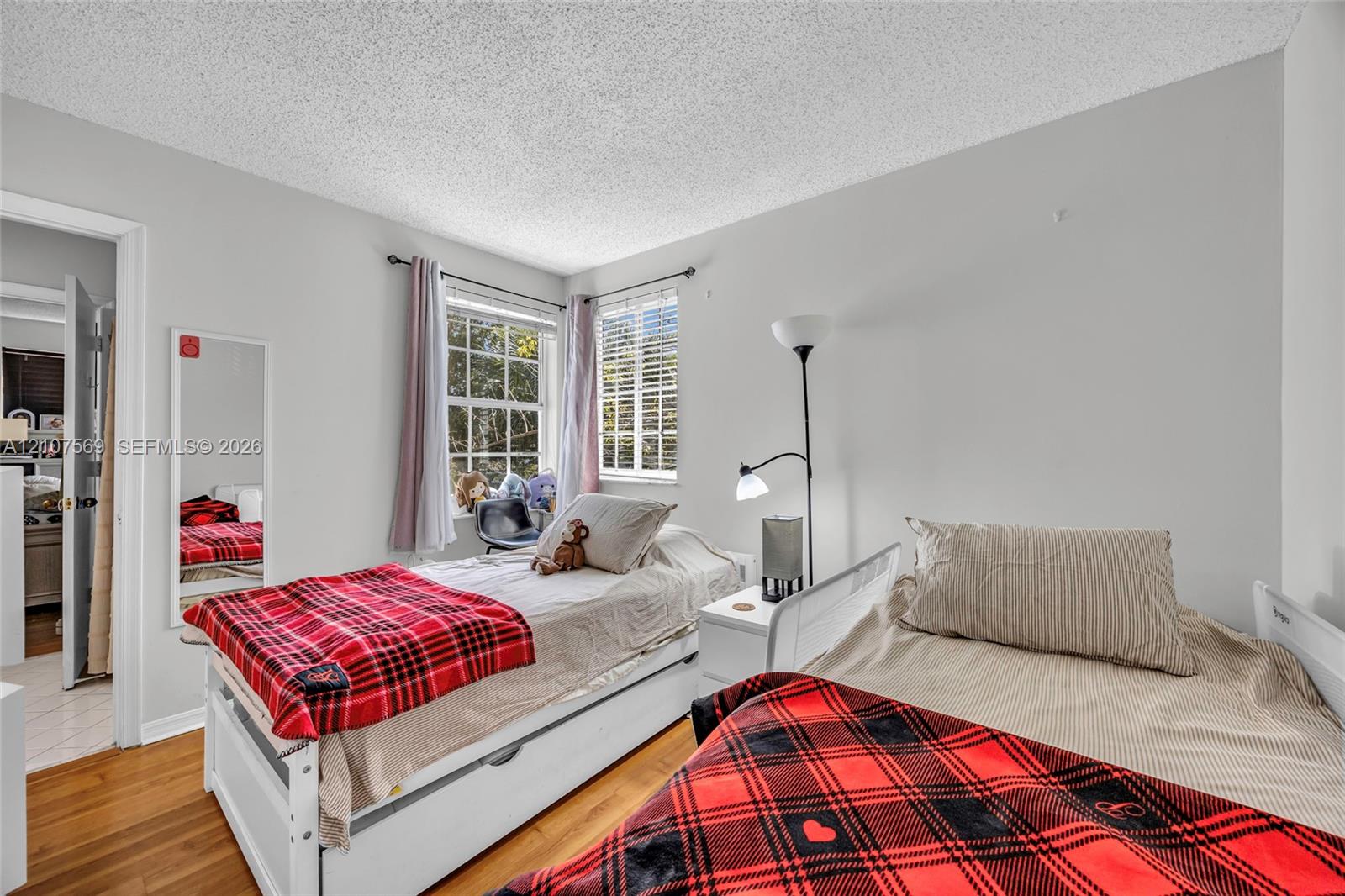 Neutral-toned room featuring wood-finish flooring and dual windows with horizontal blinds