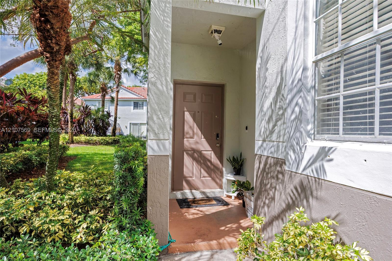 Covered entryway featuring a solid-panel entry door, exterior recessed lighting, and a multi-pane window with integrated blinds