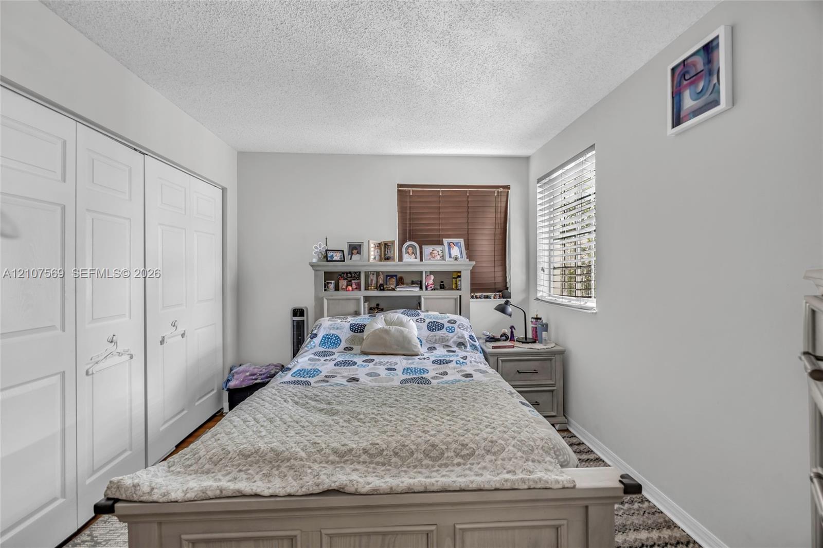 Room featuring white paneled double-door closets and horizontal window blinds
