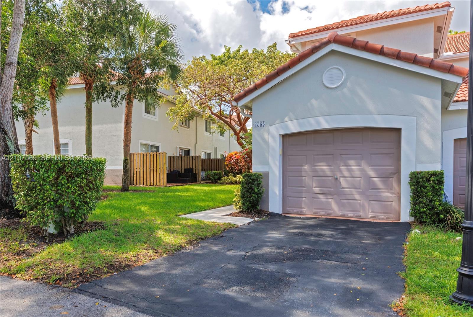 Stucco exterior featuring a tiled roof and single-car garage with asphalt driveway