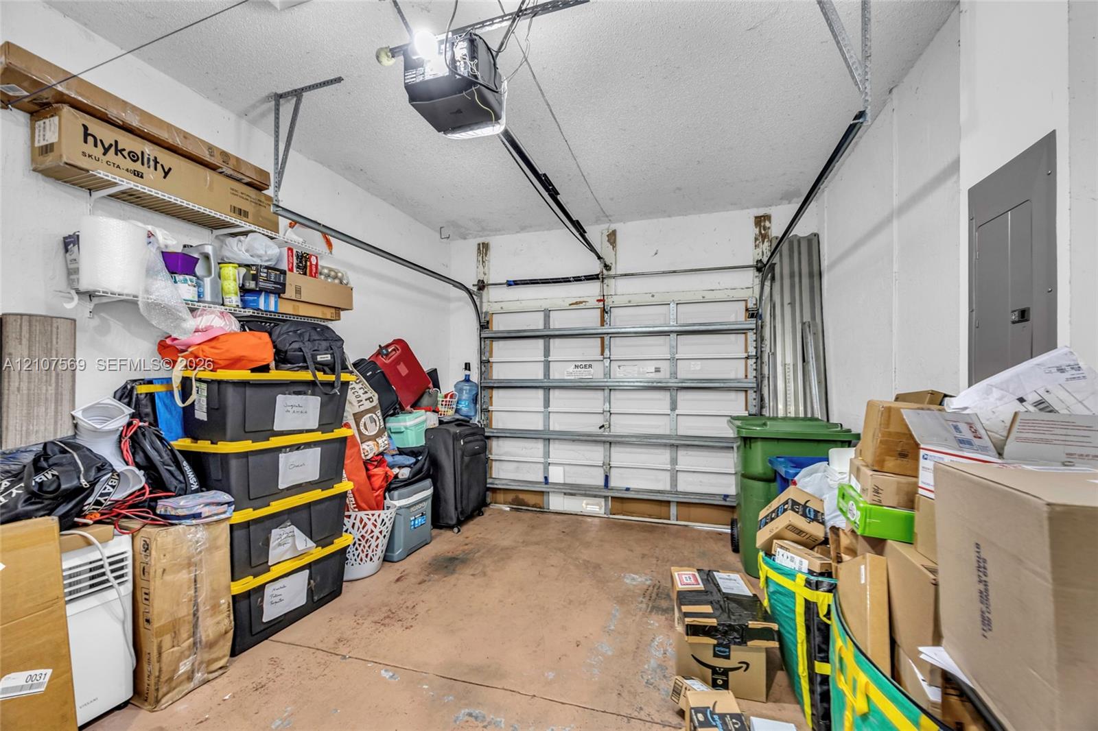 Enclosed garage featuring a sectional metal overhead door, concrete flooring, and an integrated electrical service panel