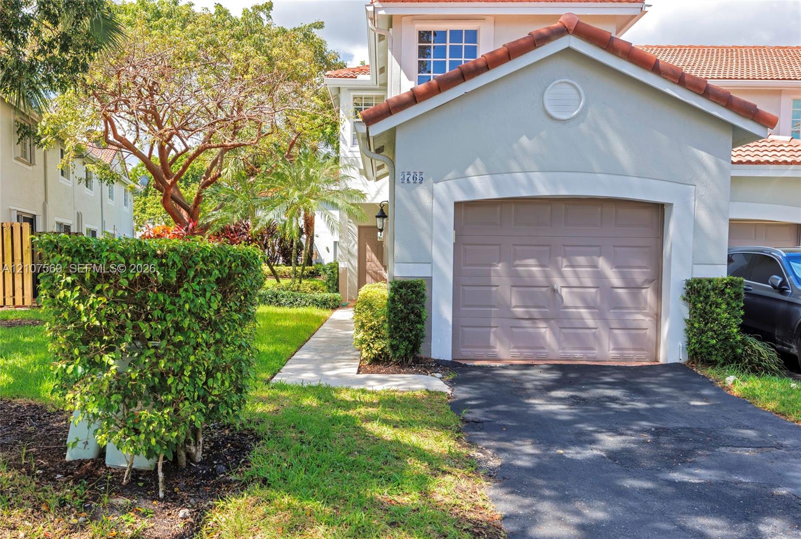 Two-story exterior featuring a clay tile roof, stucco facade, and an attached single-car garage
