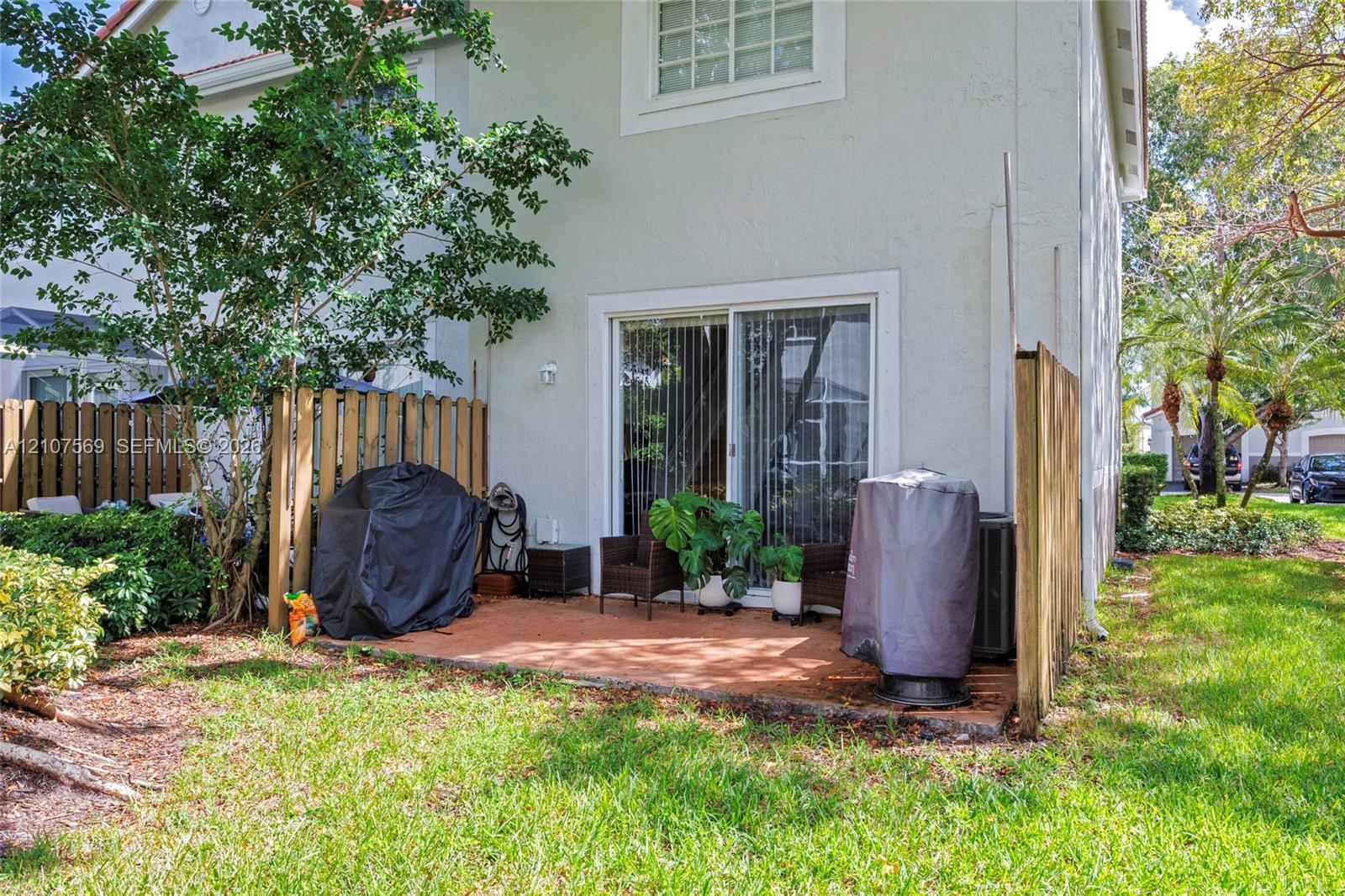 Stucco exterior featuring a sliding glass door, paved patio, and wood privacy fencing