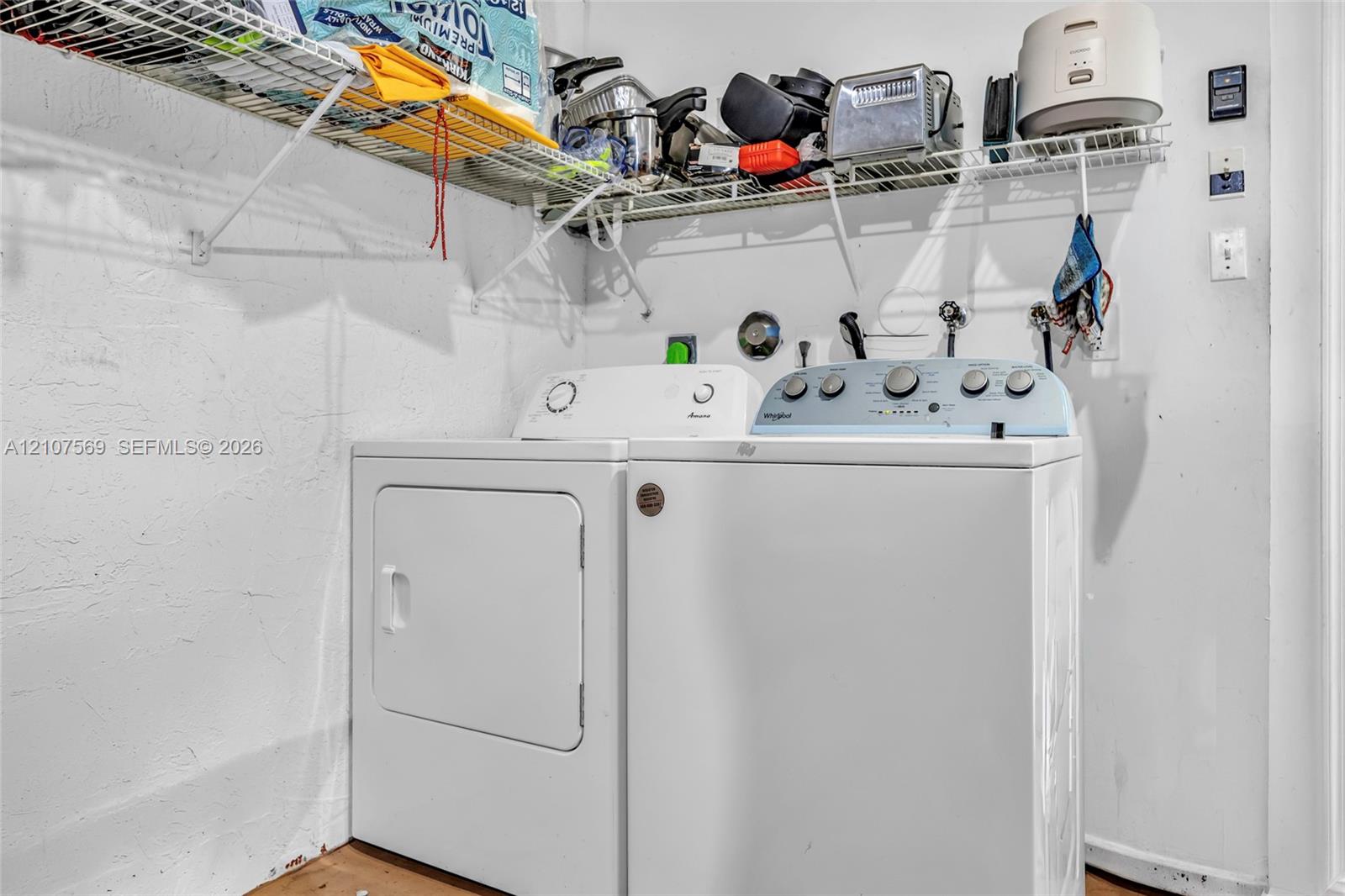 Laundry room area featuring dual appliance hookups and wire-frame overhead shelving