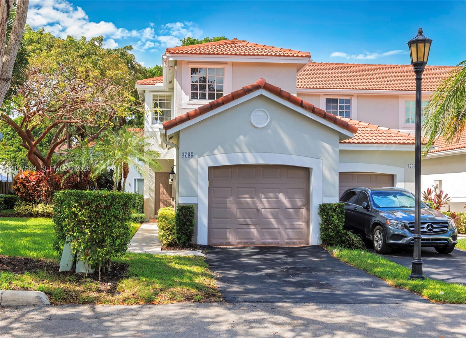 Two-story exterior featuring a clay tile roof, stucco facade, and an integrated single-car garage