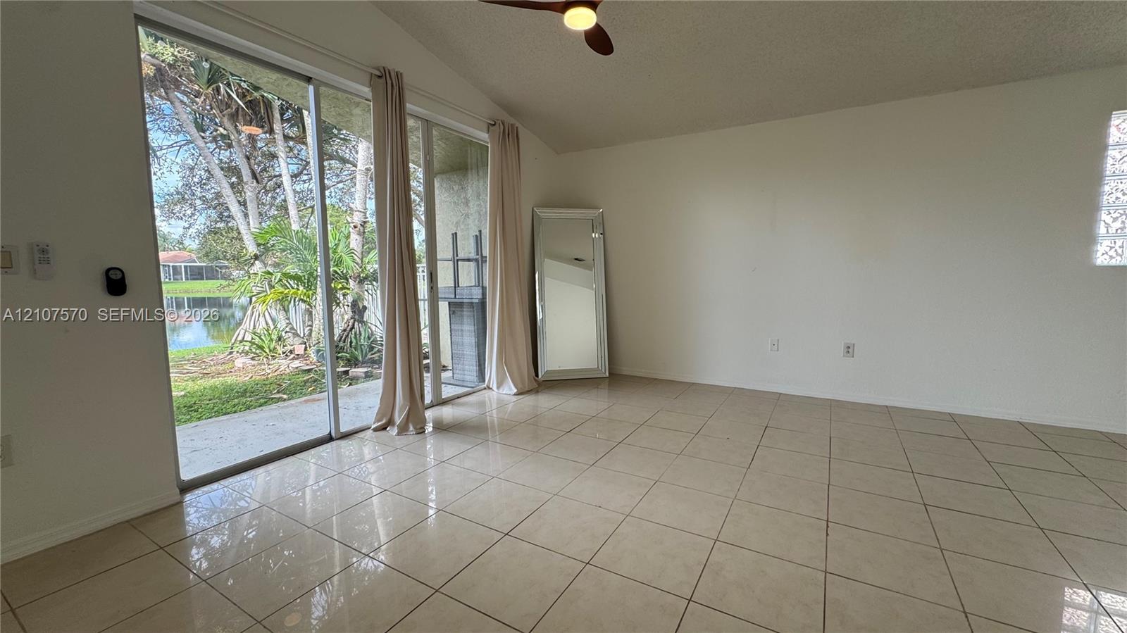 Sliding glass doors featuring ceramic tile flooring, a vaulted ceiling, a ceiling fan with integrated lighting, and glass block accent windows