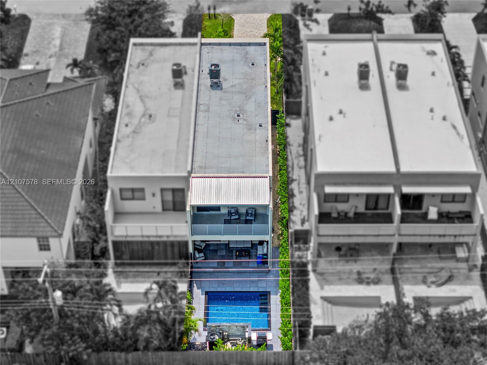 Aerial perspective of a multi-level residence featuring a flat roofline, two levels of private balconies, a rear swimming pool with integrated hardscaping, and perimeter landscaping