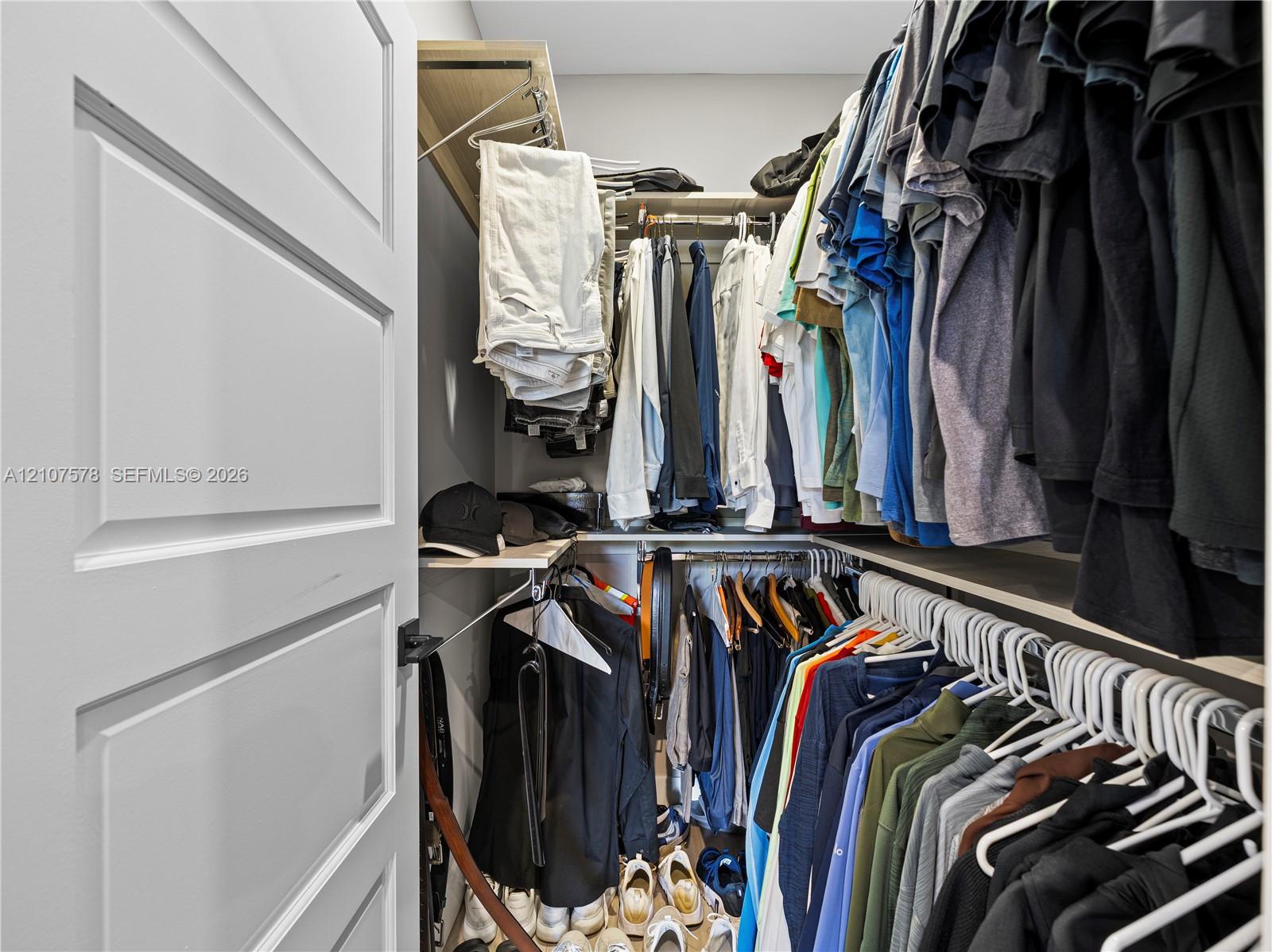 Reach-in closet featuring multi-level wood-finish shelving and integrated hanging rods