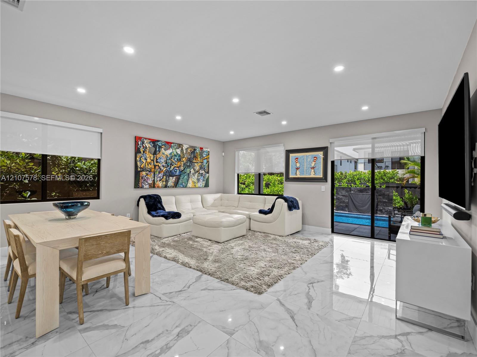 Open-concept living space featuring high-gloss large-format floor tiling, recessed lighting, and sliding glass doors with exterior patio and pool access