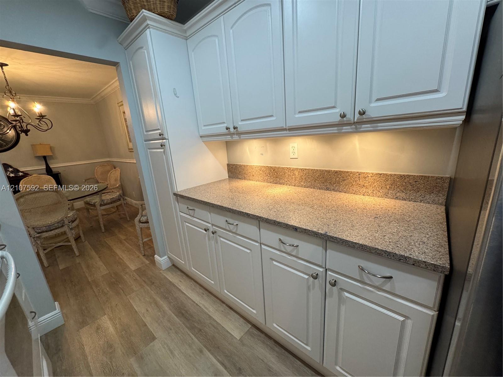 Custom cabinetry featuring raised-panel doors, neutral stone-patterned countertops, and integrated under-cabinet lighting