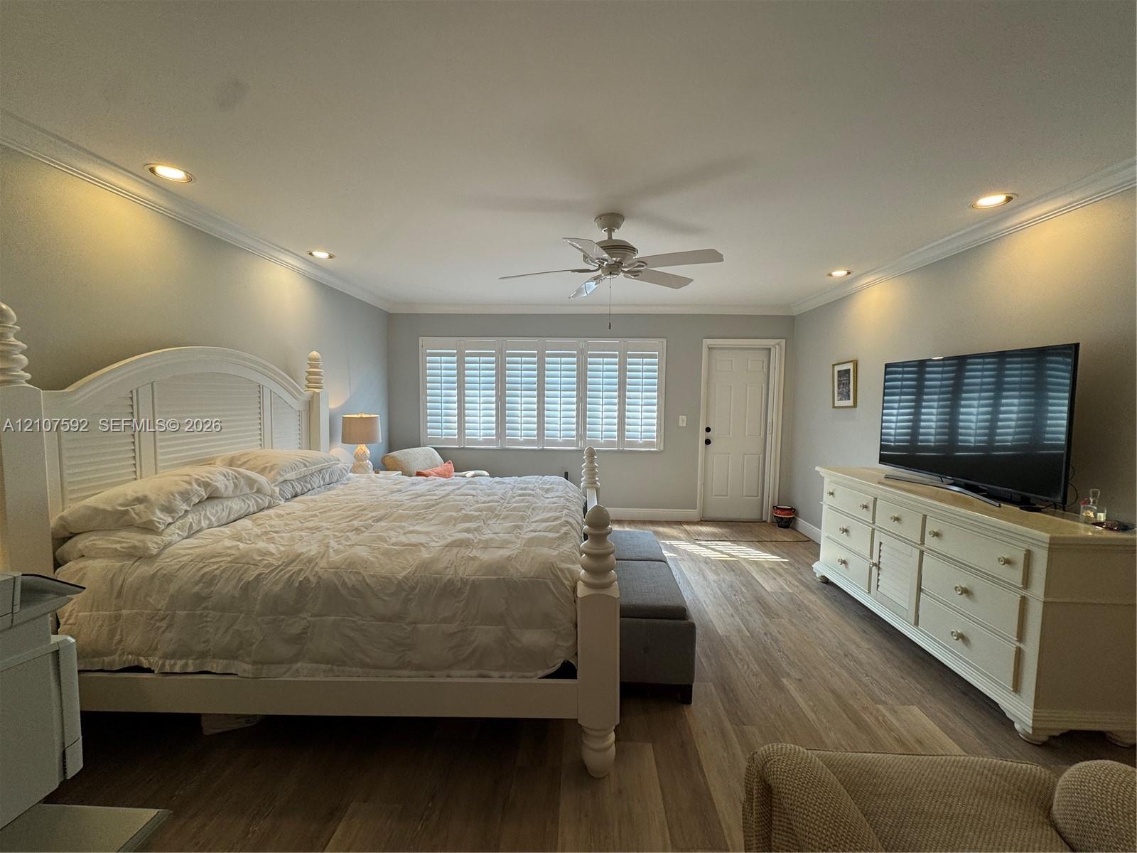 Room featuring wood-finish flooring, crown molding, recessed lighting, a ceiling fan, and plantation shutters