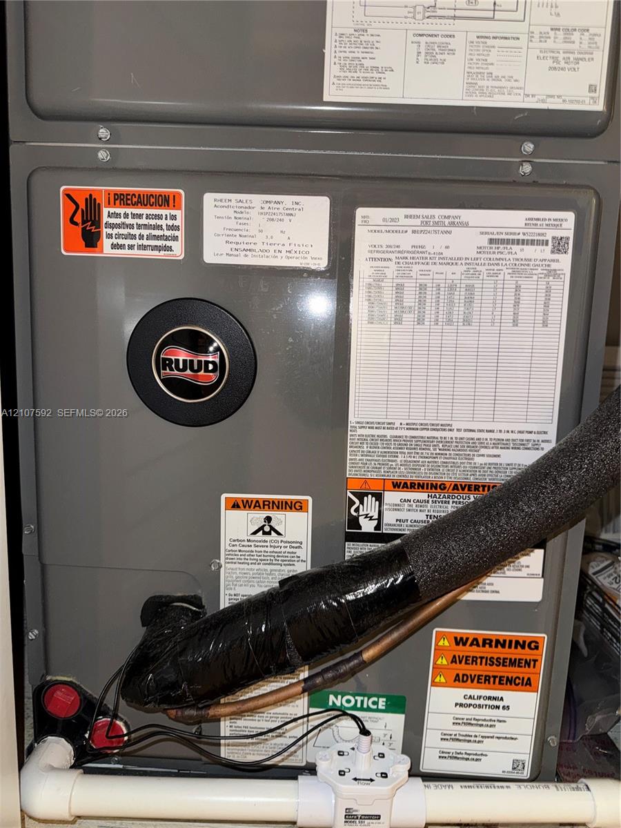 Ruud heating and cooling system featuring metallic grey finish, insulated copper refrigerant lines, and PVC drainage piping