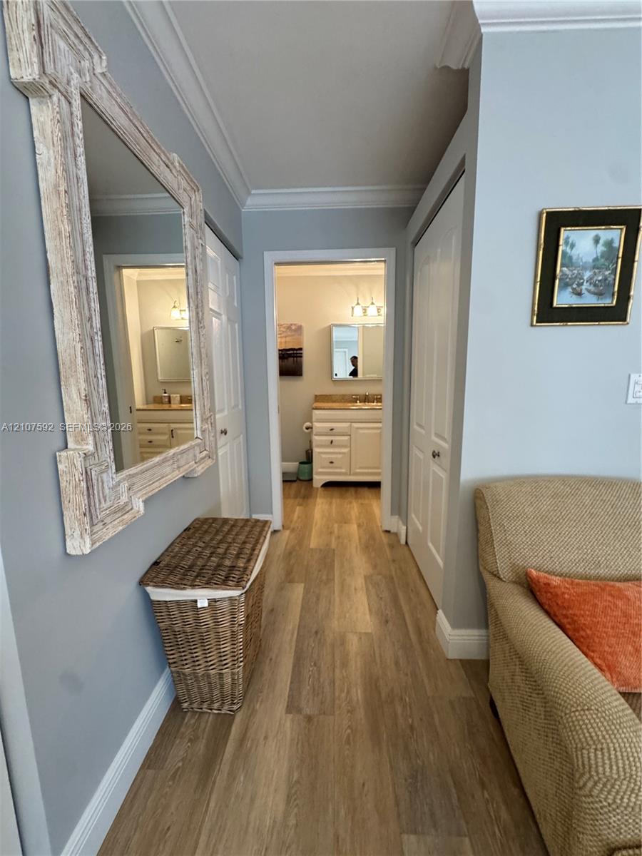 Wood-finish flooring, white paneled interior doors, and crown molding
