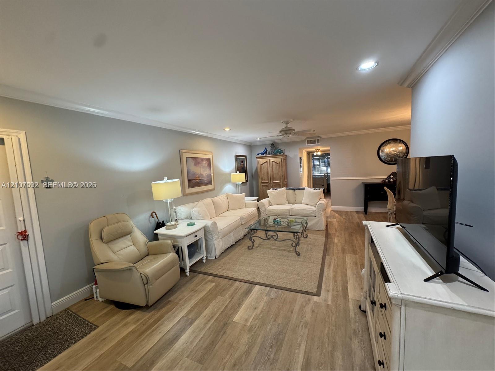 Living area featuring wood-finish flooring, crown molding, recessed lighting, and a ceiling fan Living area featuring wood-finish flooring, crown molding, recessed lighting, and a ceiling fan