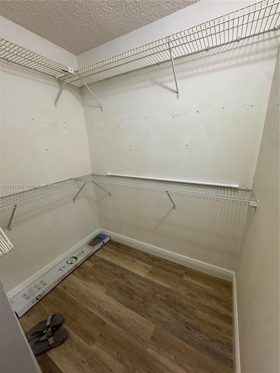 Walk-in storage space featuring wood-finish flooring and tiered metal wire shelving