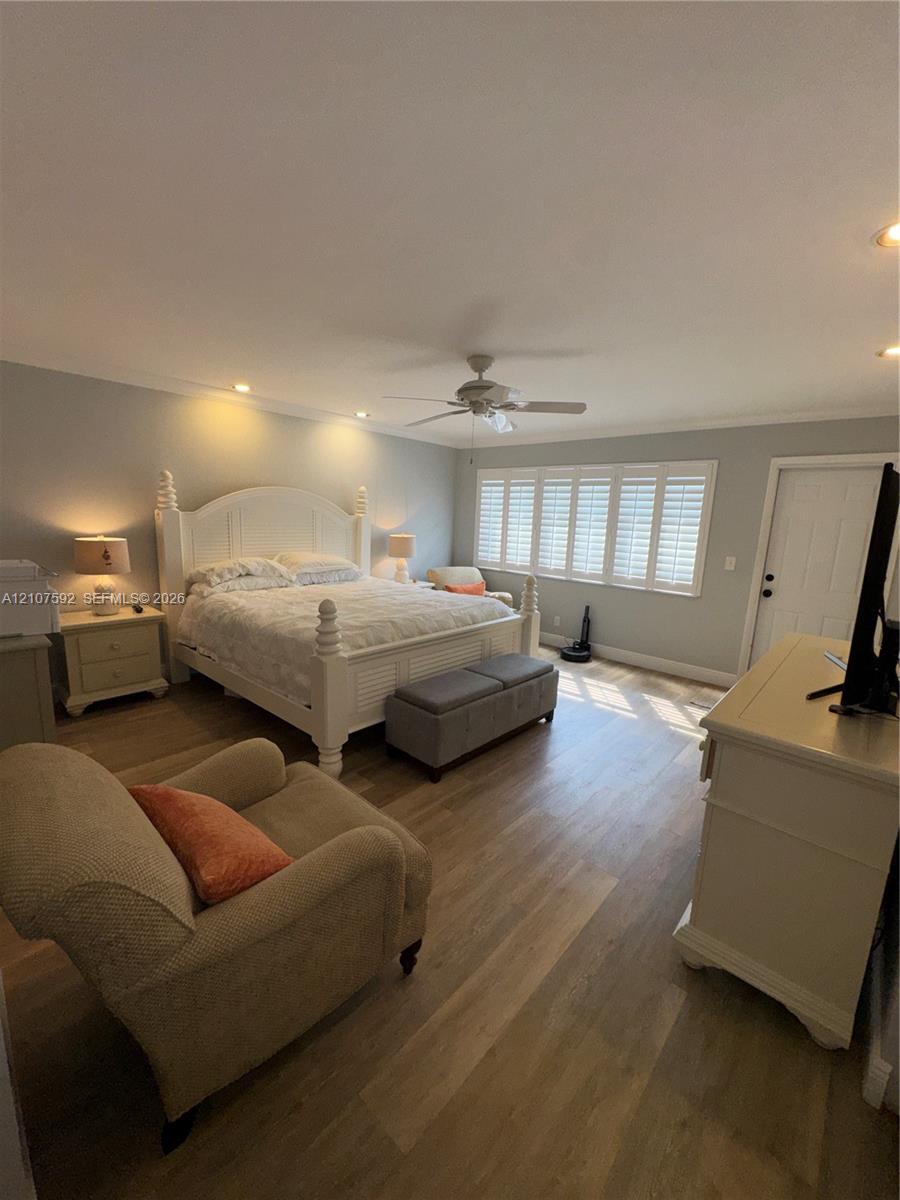 Room featuring wood-finish flooring, plantation shutters, crown molding, recessed lighting, and a ceiling fan