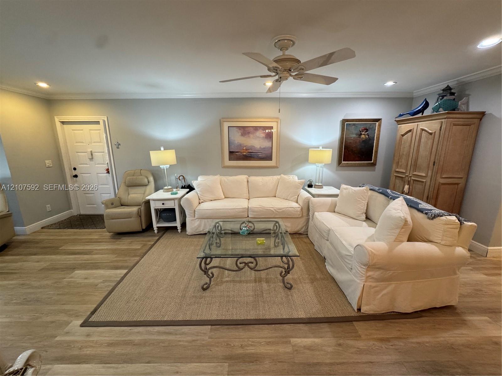 Living area featuring wood-finish flooring, a ceiling fan with integrated lighting, and recessed ceiling lights Living area featuring wood-finish flooring, a ceiling fan with integrated lighting, and recessed ceiling lights
