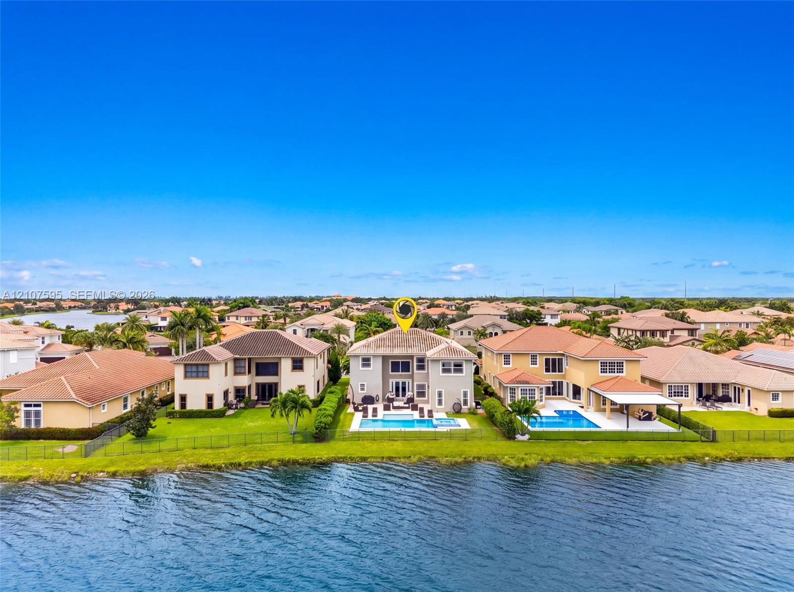 Waterfront residence featuring a private swimming pool, concrete tile roof, and rear patio hardscaping