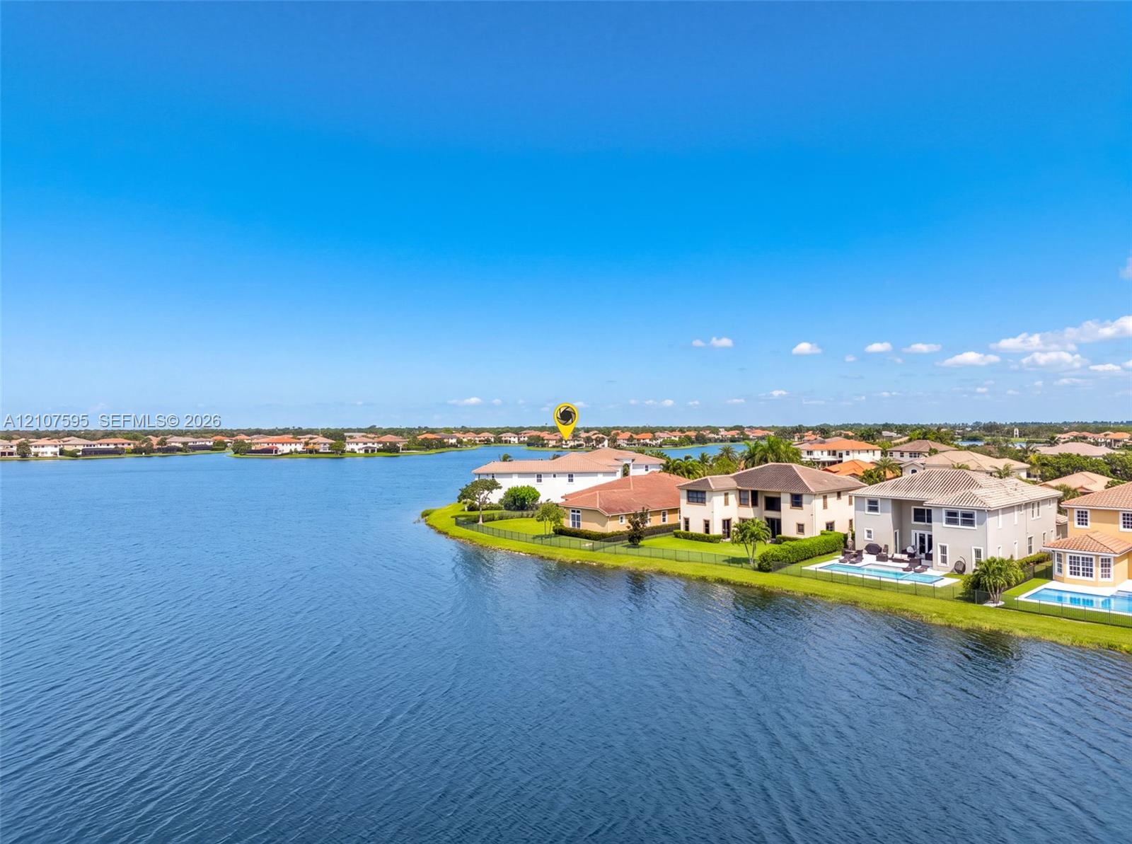 Waterfront property featuring a tile roof, manicured lawn, and perimeter fencing