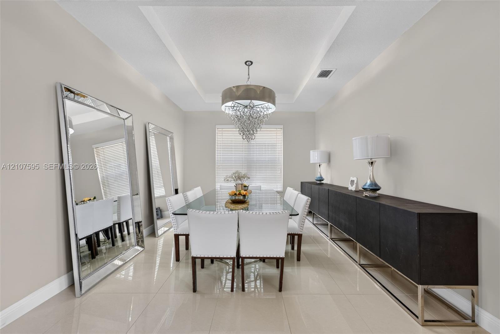 Tray ceiling featuring recessed lighting, polished tile flooring, and a central tiered crystal chandelier