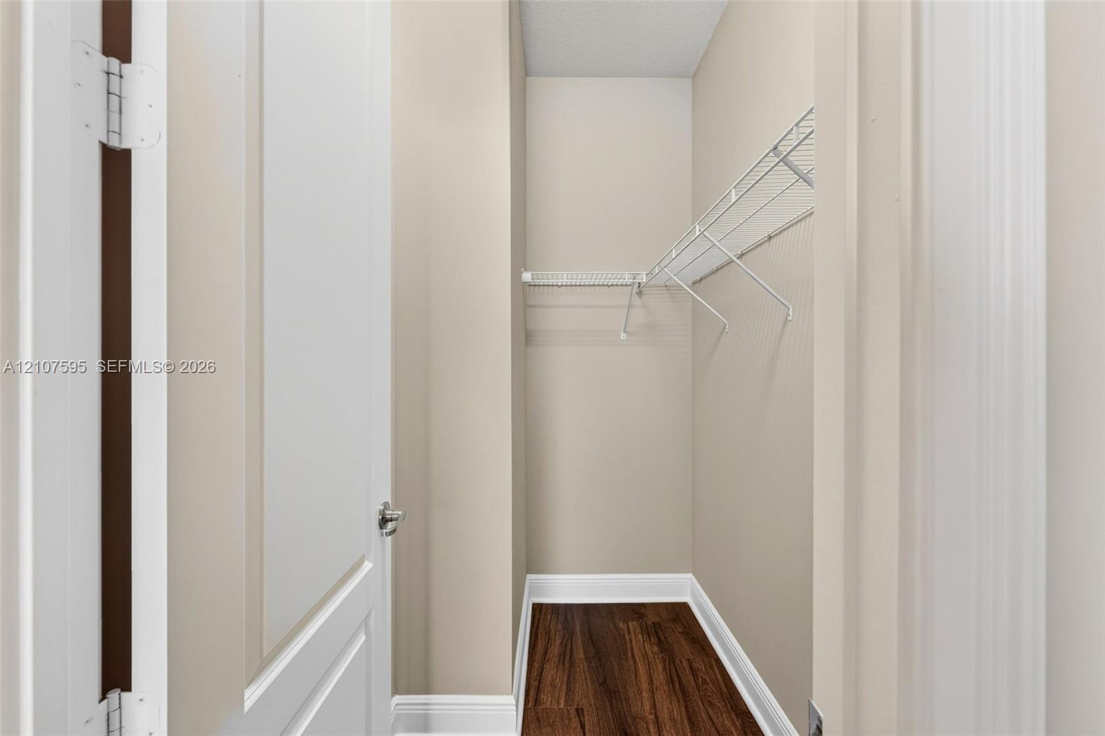 Walk-in closet featuring neutral wall tones, wood-finish flooring, and white wire shelving