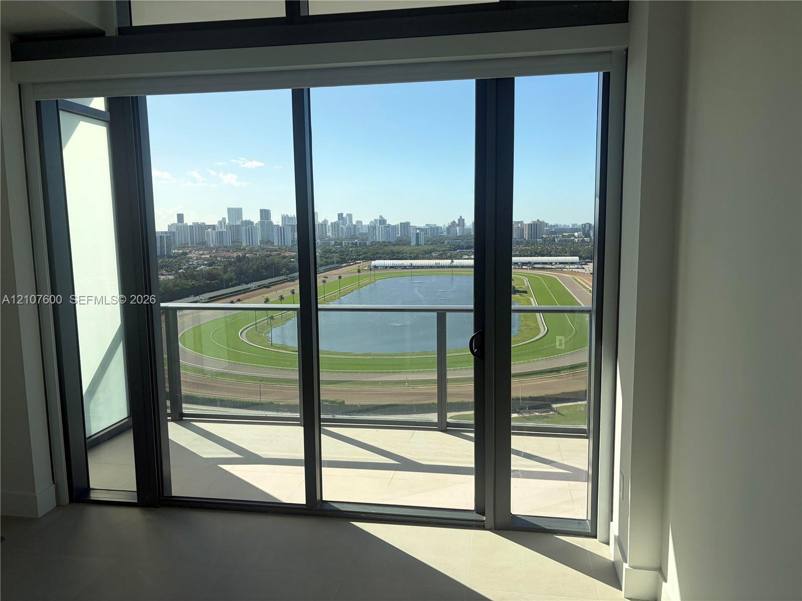 Floor-to-ceiling sliding glass doors, private balcony, metal railing, and expansive cityscape scenery