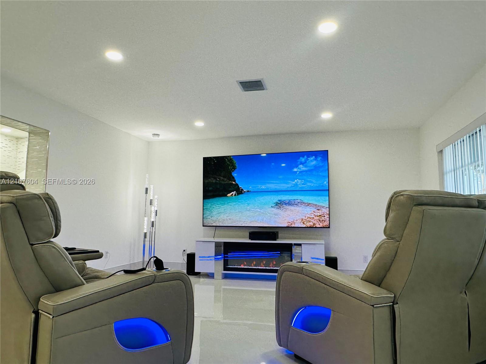 Recessed ceiling lighting, polished flooring, and a built-in electric fireplace unit with a high-gloss finish