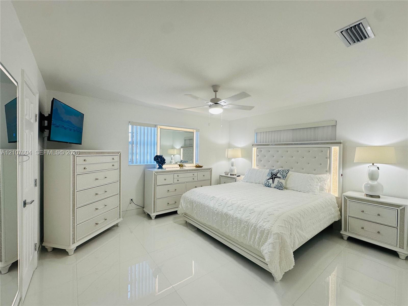 Neutral-toned room featuring large-format tile flooring, a recessed ceiling-mounted fan, and vertical blinds