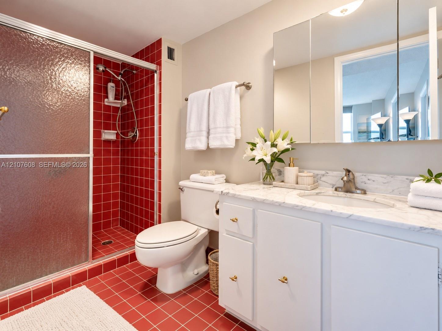 Vanity with stone countertop and integrated oval sink, built-in medicine cabinet, walk-in shower with textured glass door, and tiled flooring