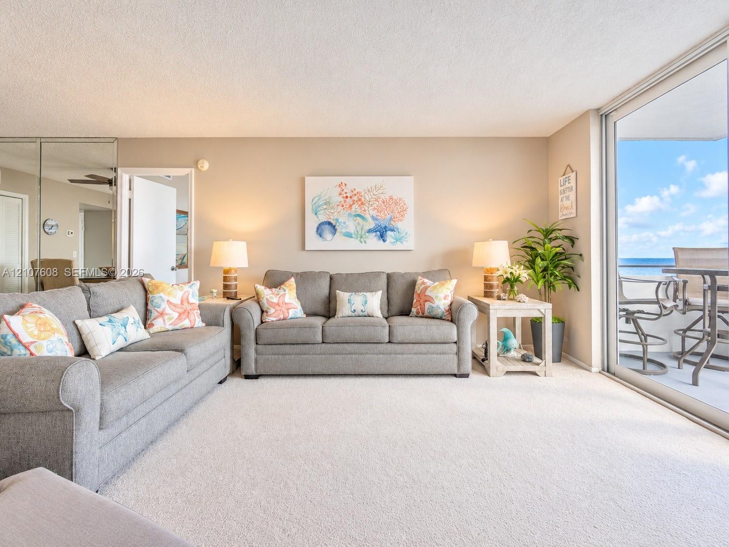 Full-height mirrored wall paneling, wall-to-wall carpeting, and sliding glass doors with access to an exterior balcony