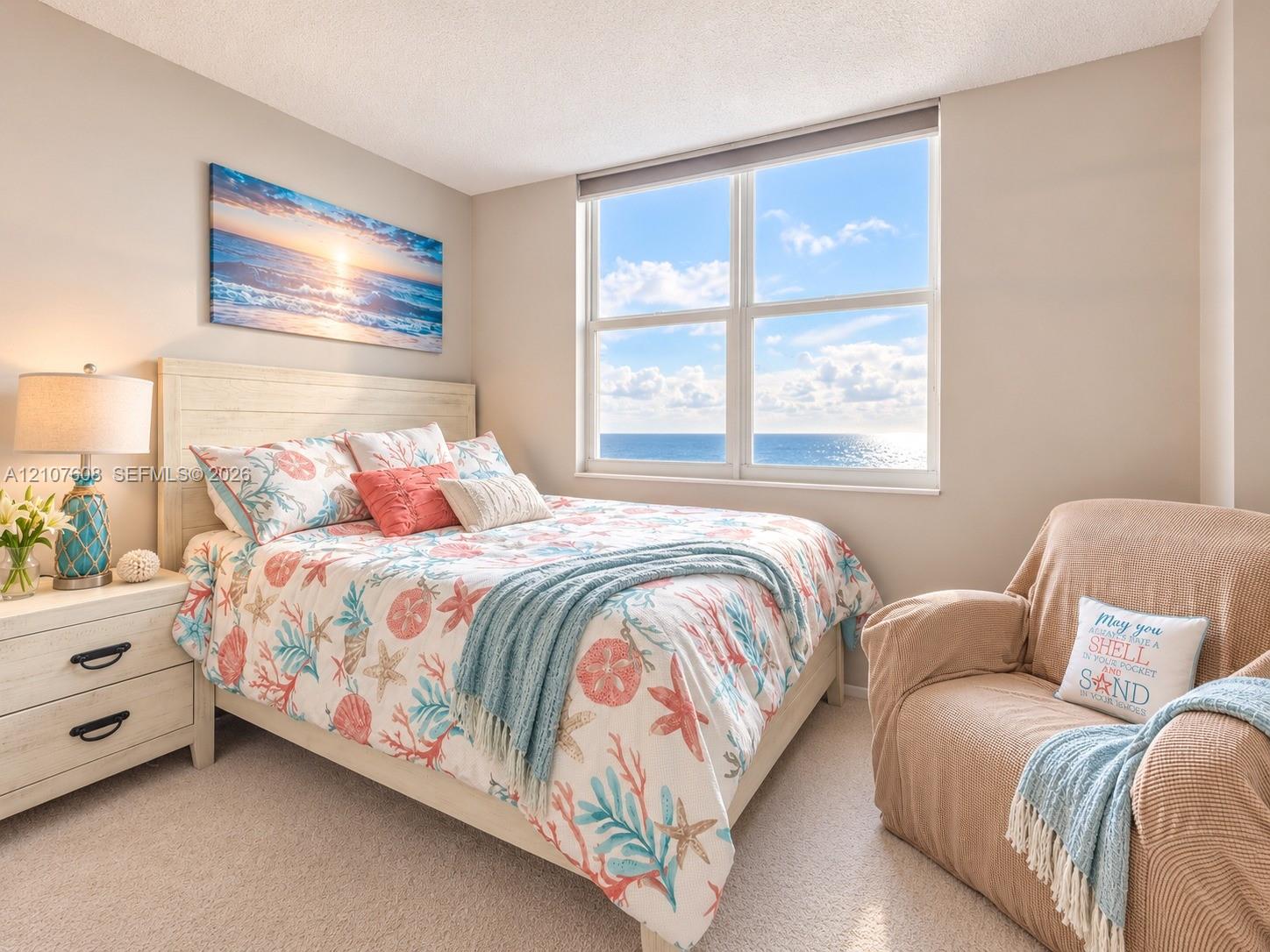 Neutral wall tones, carpeted flooring, and a large multi-pane window featuring an ocean horizon backdrop