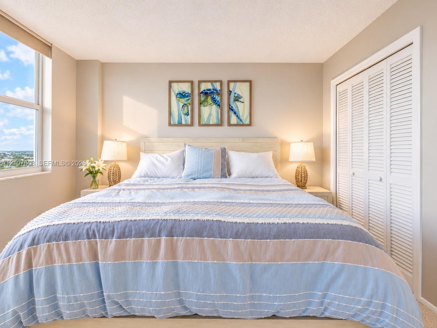 Large window providing natural light, white louvered closet doors, and neutral wall tones