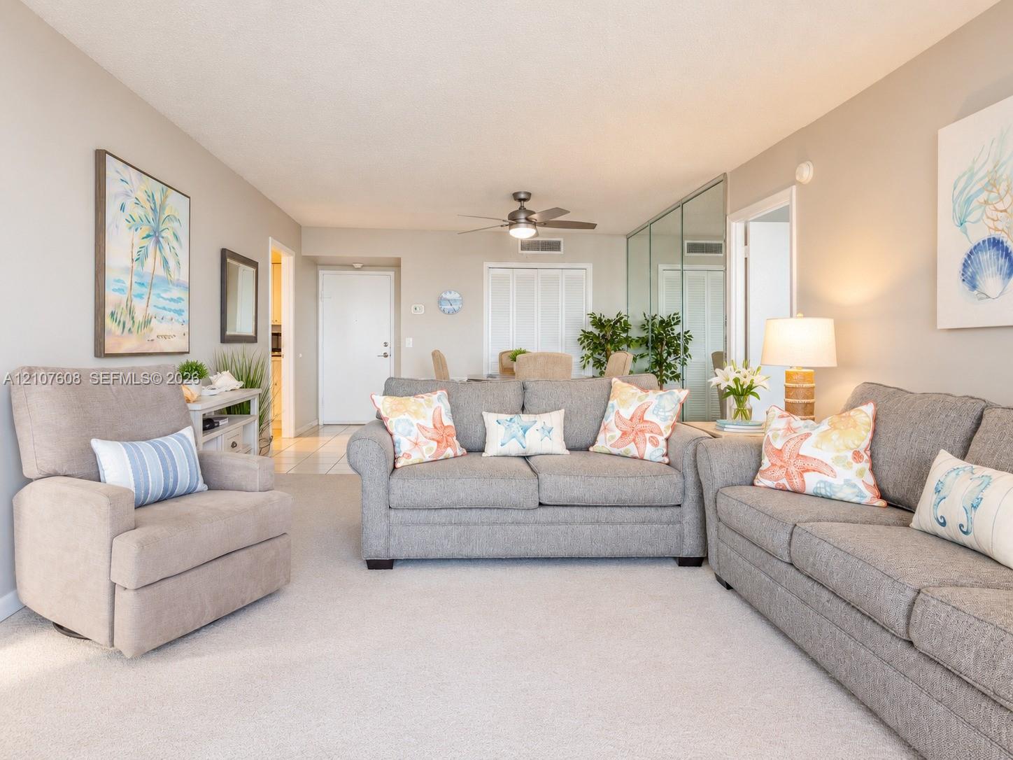 Neutral-toned interior featuring wall-to-wall carpeting, mirrored closet doors, a central ceiling fan with integrated lighting, and multiple louvered-door closets