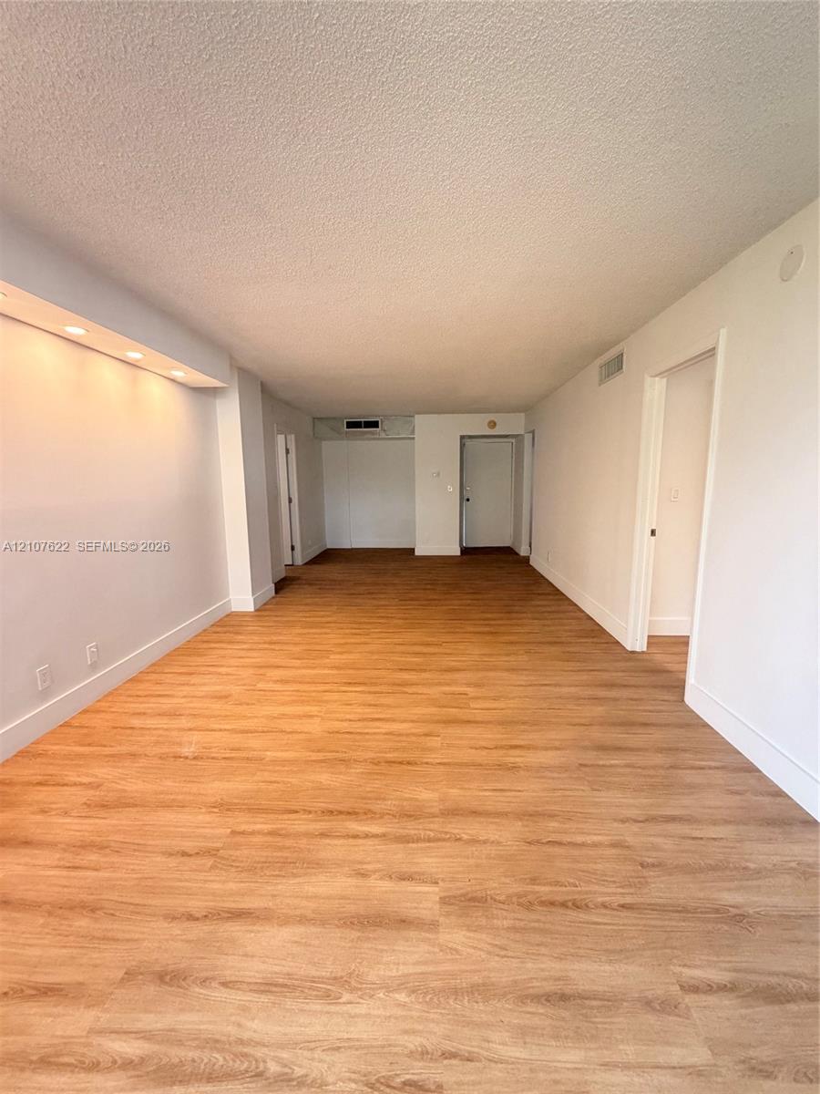 Open-concept interior featuring wood-finish flooring, recessed architectural soffit lighting, and neutral wall tones