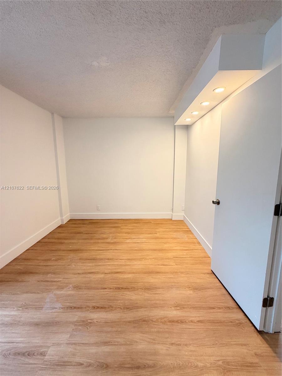 Room featuring wood-finish flooring, recessed lighting, and a soffit ceiling detail
