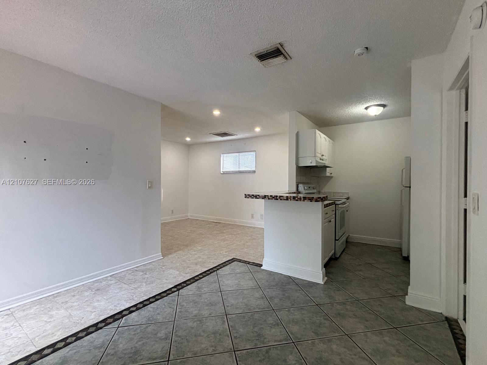 Kitchen featuring a breakfast bar, white cabinetry, and tile flooring