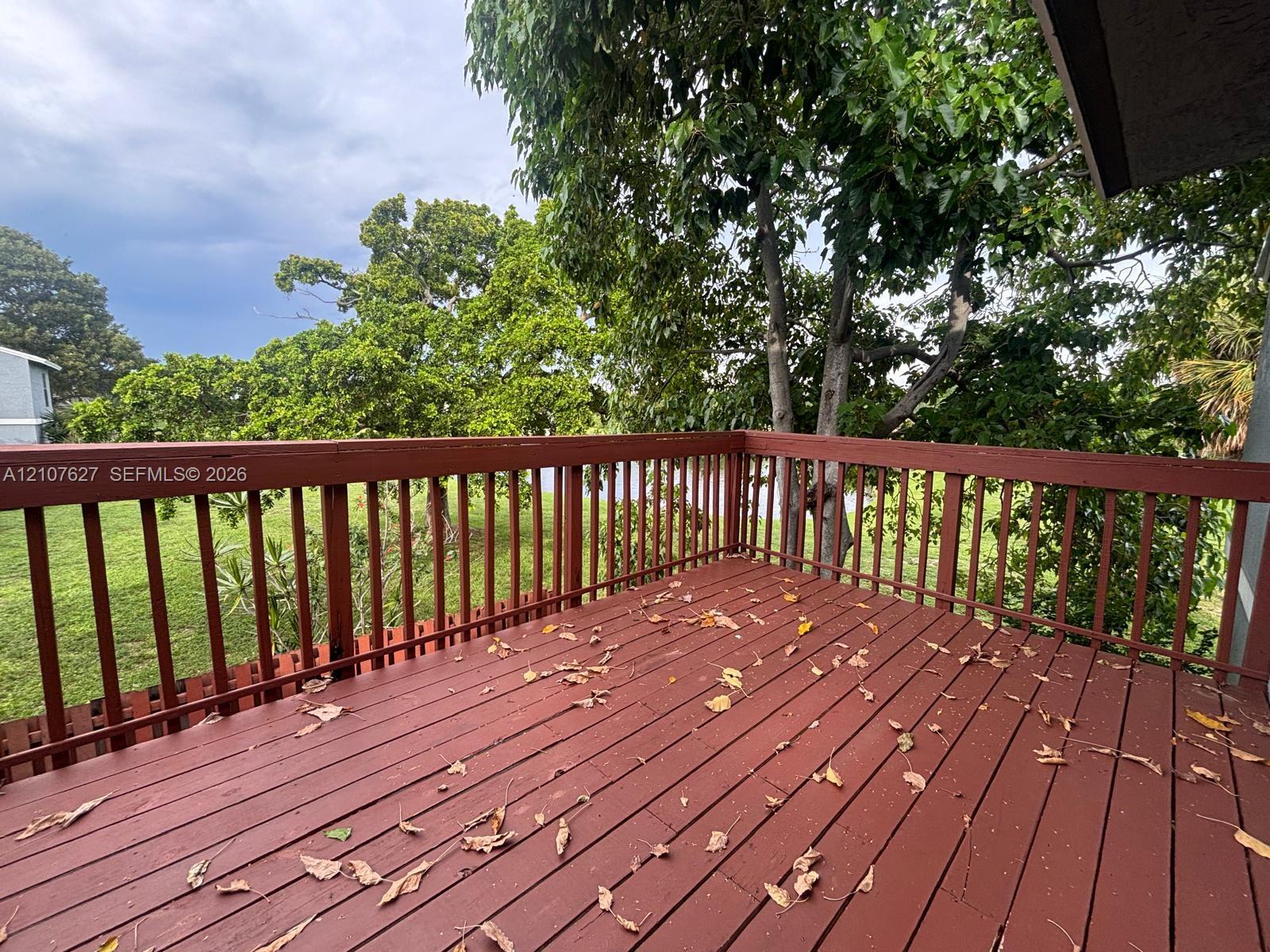Elevated deck featuring wood-finish decking, horizontal railings, and mature trees