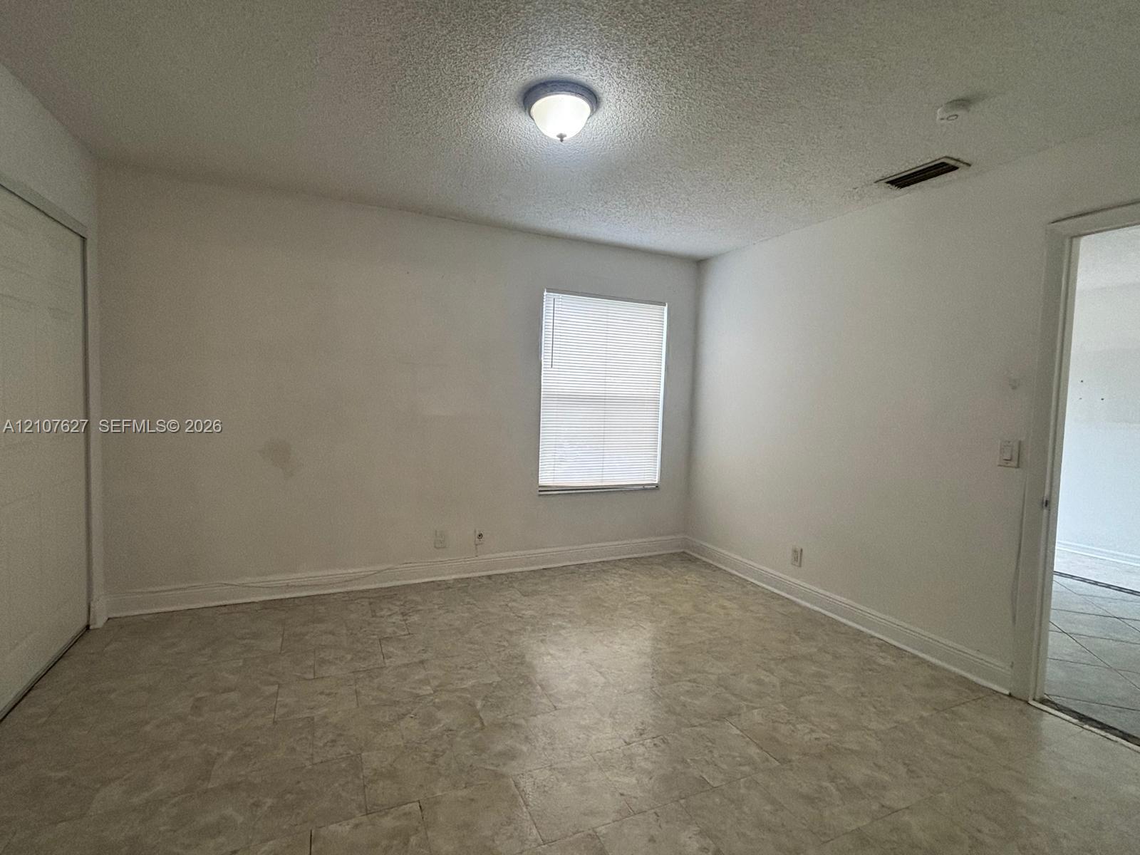 Room featuring neutral wall finishes, tile flooring, a window with horizontal blinds, and a built-in closet with sliding doors