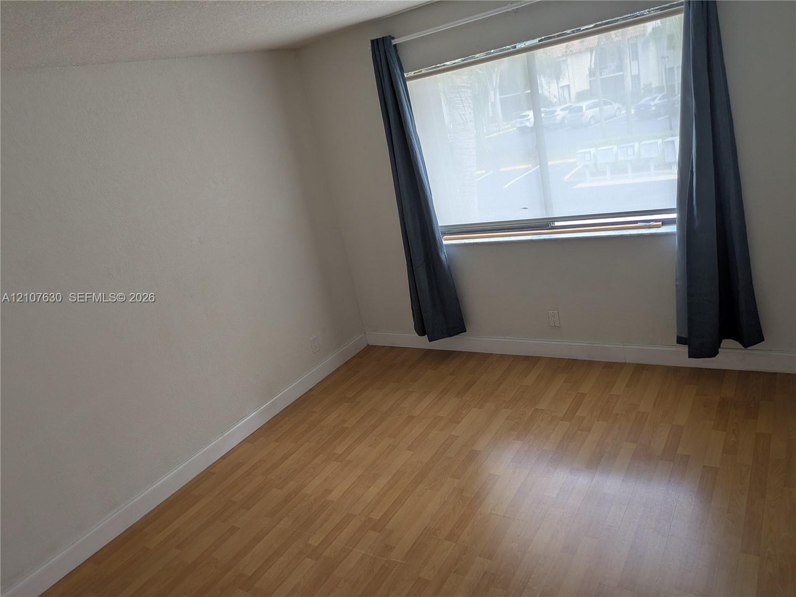 Room featuring wood-finish flooring, a large window, and neutral walls