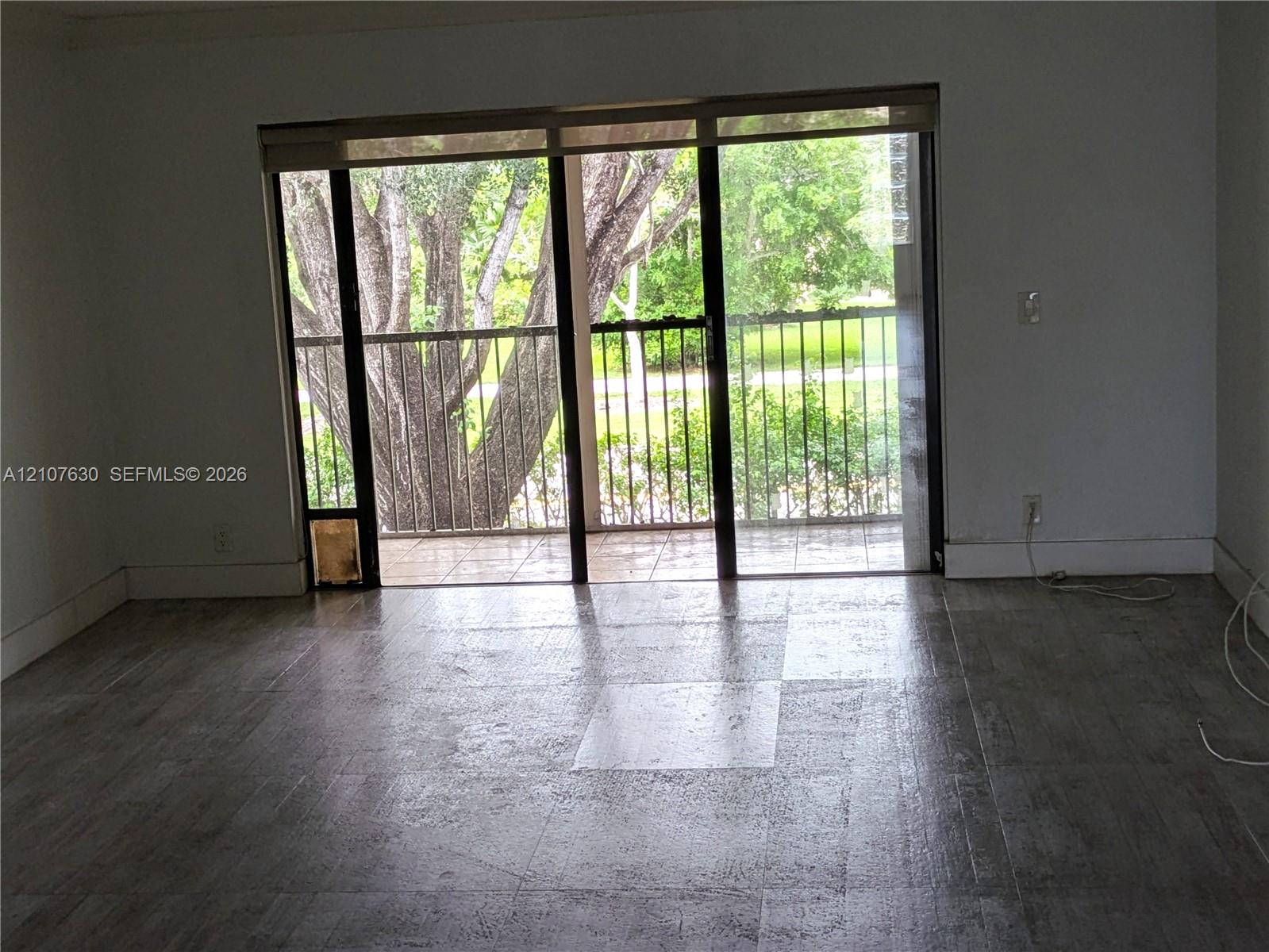 Floor-to-ceiling sliding glass door with integrated blinds, providing access to a covered exterior balcony featuring a metal railing