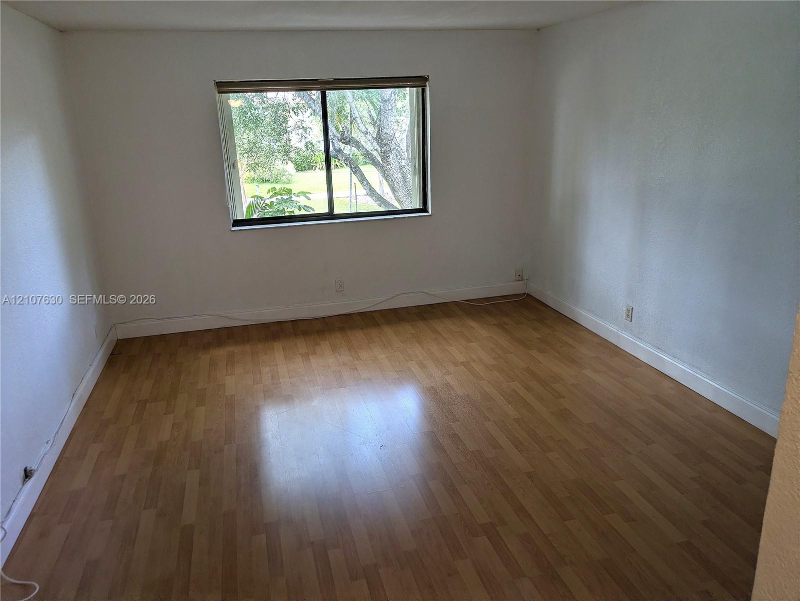 Interior space featuring wood-finish flooring, white walls, and a sliding glass window