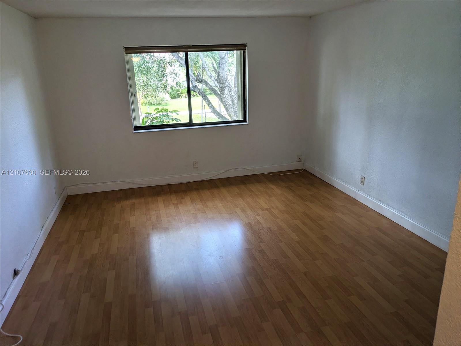 Room featuring wood-finish flooring, white walls, and a horizontal sliding window